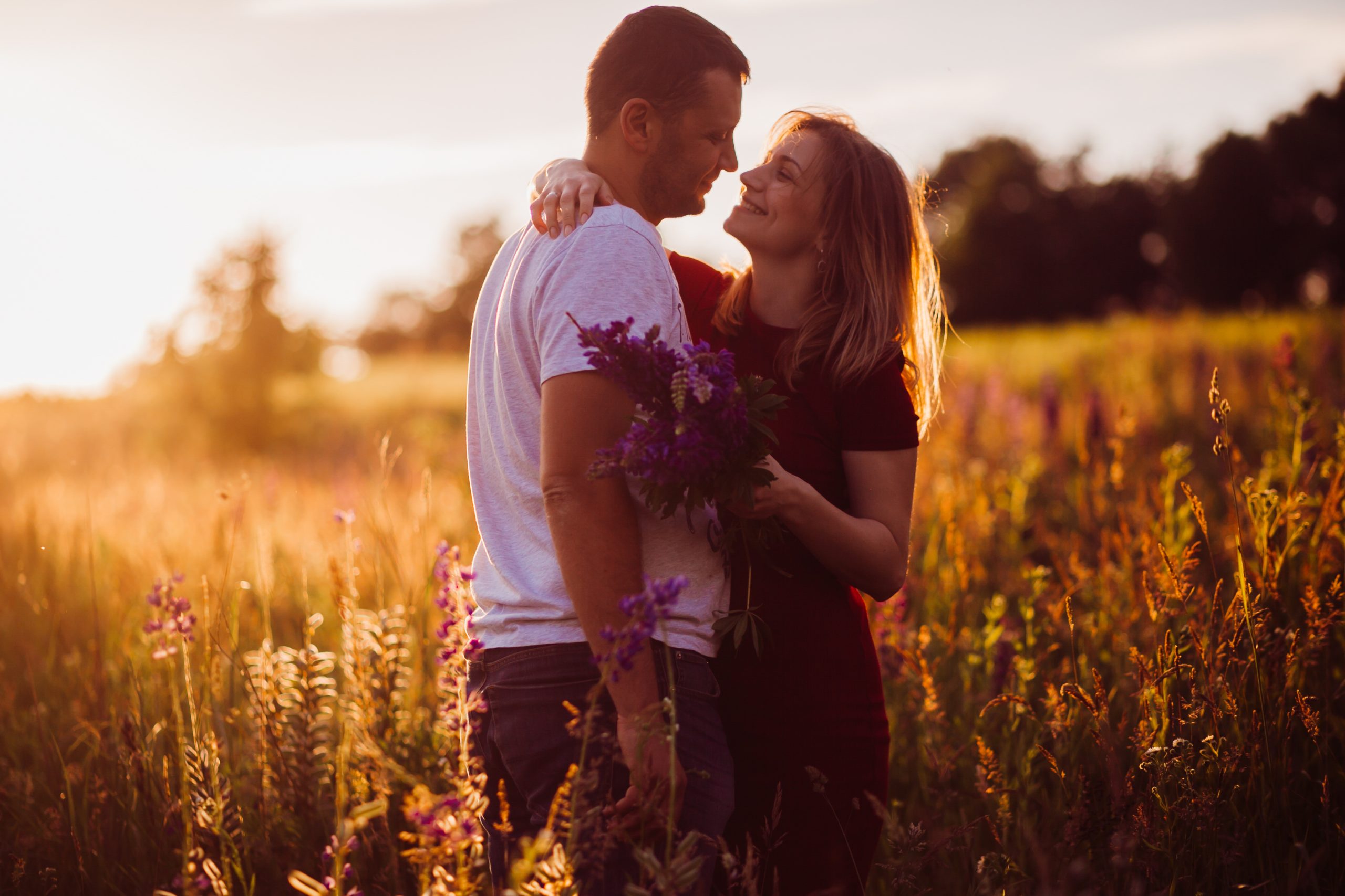 cheerful couple hugs each other tender standing on the green field scaled