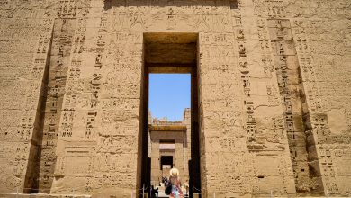 closeup shot of a female standing in front of a medinet habu temple in egypt