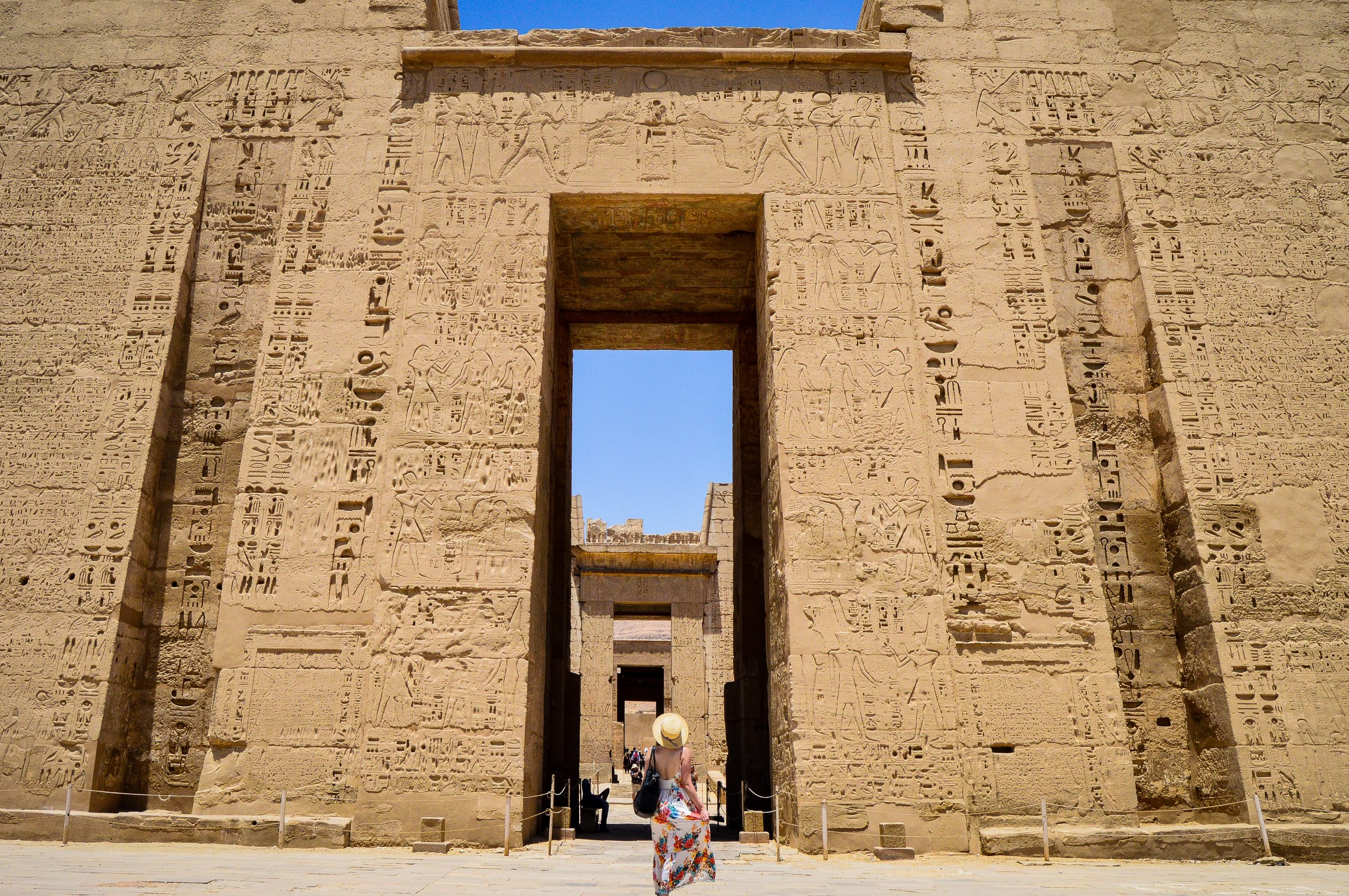 closeup shot of a female standing in front of a medinet habu temple in egypt scaled