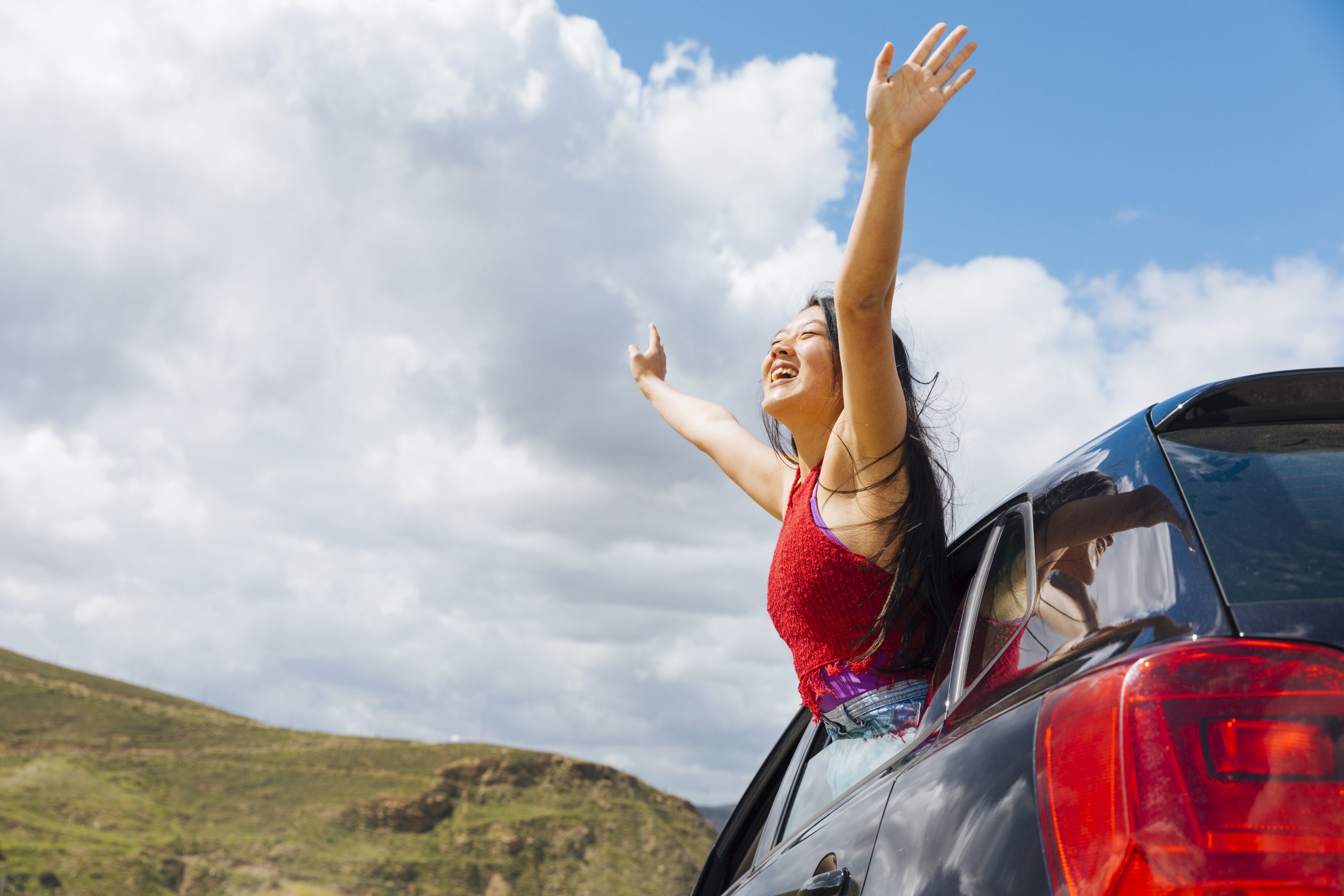 joyful young woman raising hands to sky scaled