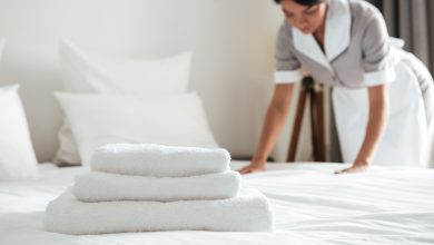 young hotel maid setting up pillow on bed
