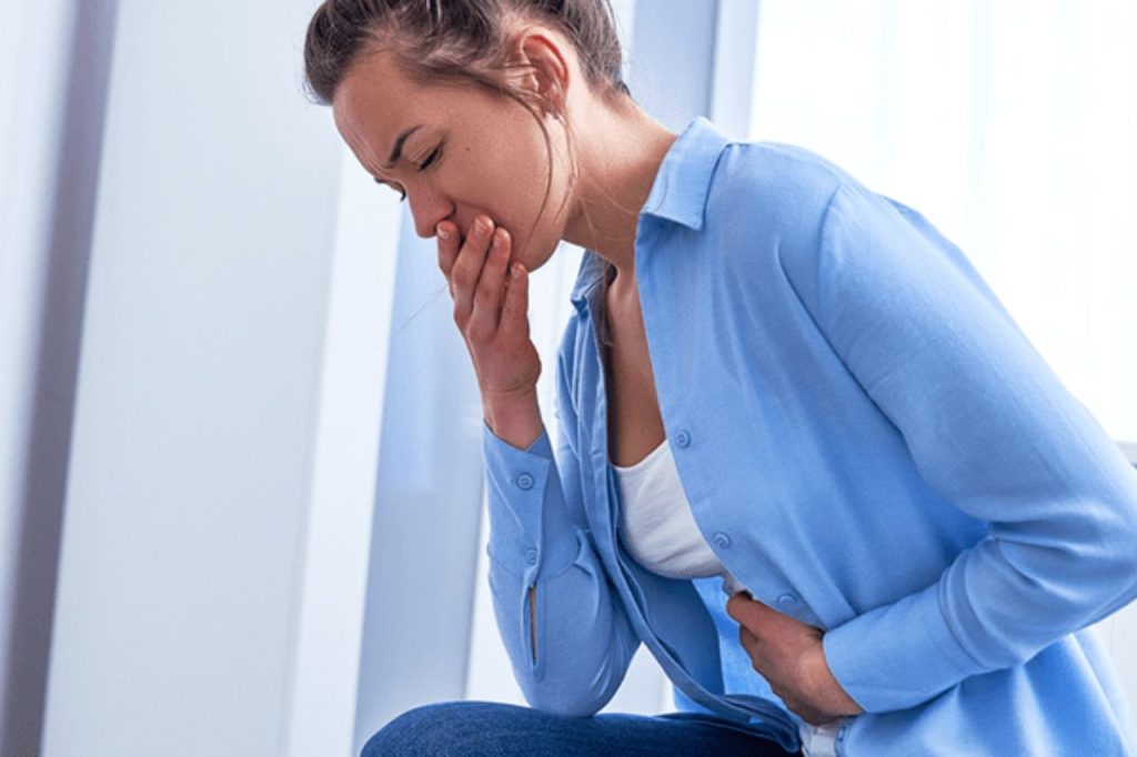 Primeiros Sinais de Gravidez: Como Identificar os Sintomas Iniciais e Confirmar com Segurança 3 Mulher sentindo enjoo e desconforto abdominal, representando os primeiros sinais de gravidez e os sintomas iniciais mais comuns no início da gestação