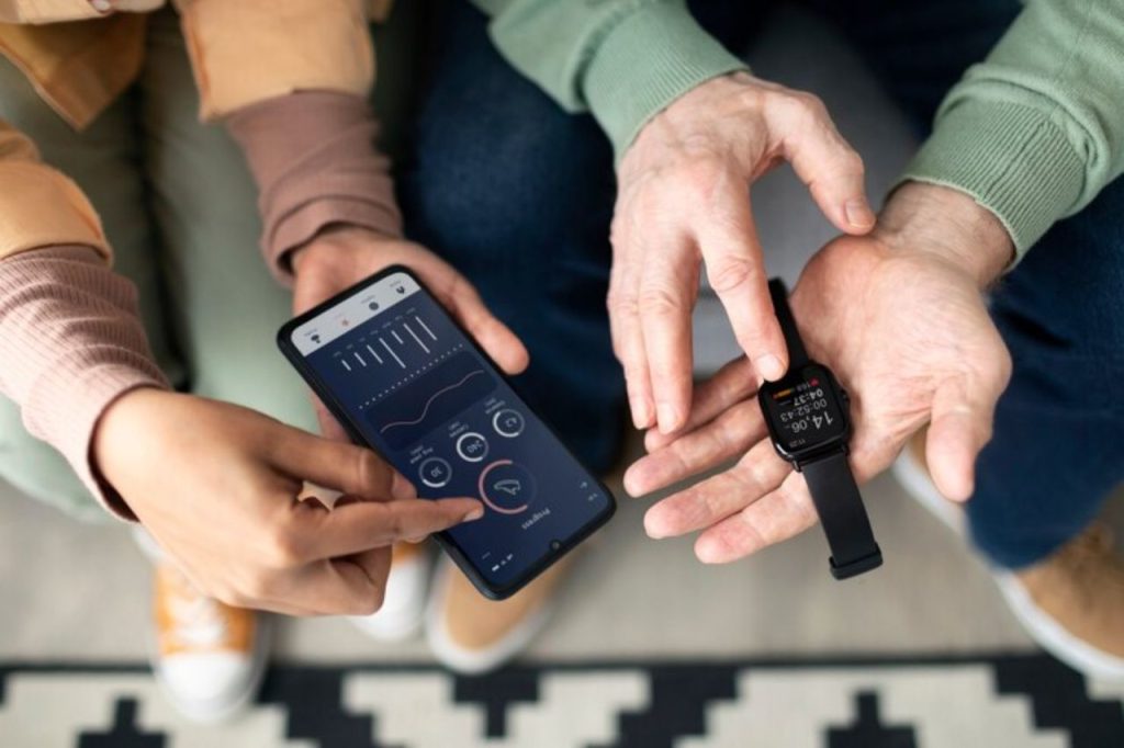 Duas pessoas utilizando smartphone e smartwatch para monitorar dados de saúde e glicose, representando o uso integrado de tecnologia no bem-estar.