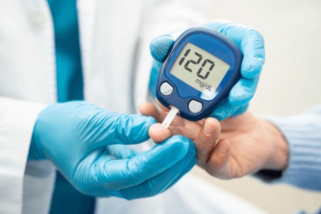 Profissional de saúde usando glicosímetro para medir os níveis de glicose no sangue de um paciente, ilustrando a importância do monitoramento regular da glicemia.