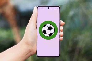Smartphone exibindo ícone de futebol na tela, representando a possibilidade de assistir futebol pelo celular com aplicativos práticos e acessíveis em qualquer lugar.